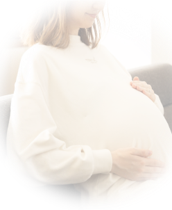 ソファに座って両手でお腹を触る女性